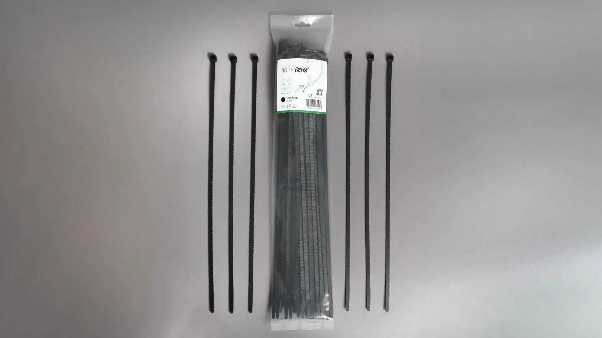 Ein Tight'n Twist Kabelbinder 504x8 mm in Schwarz liegt neben der Originalverpackung – Detailansicht des innovativen Designs